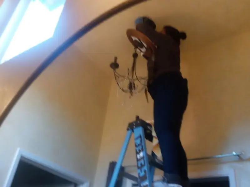 Electrician installing a chandelier in a Danville residence